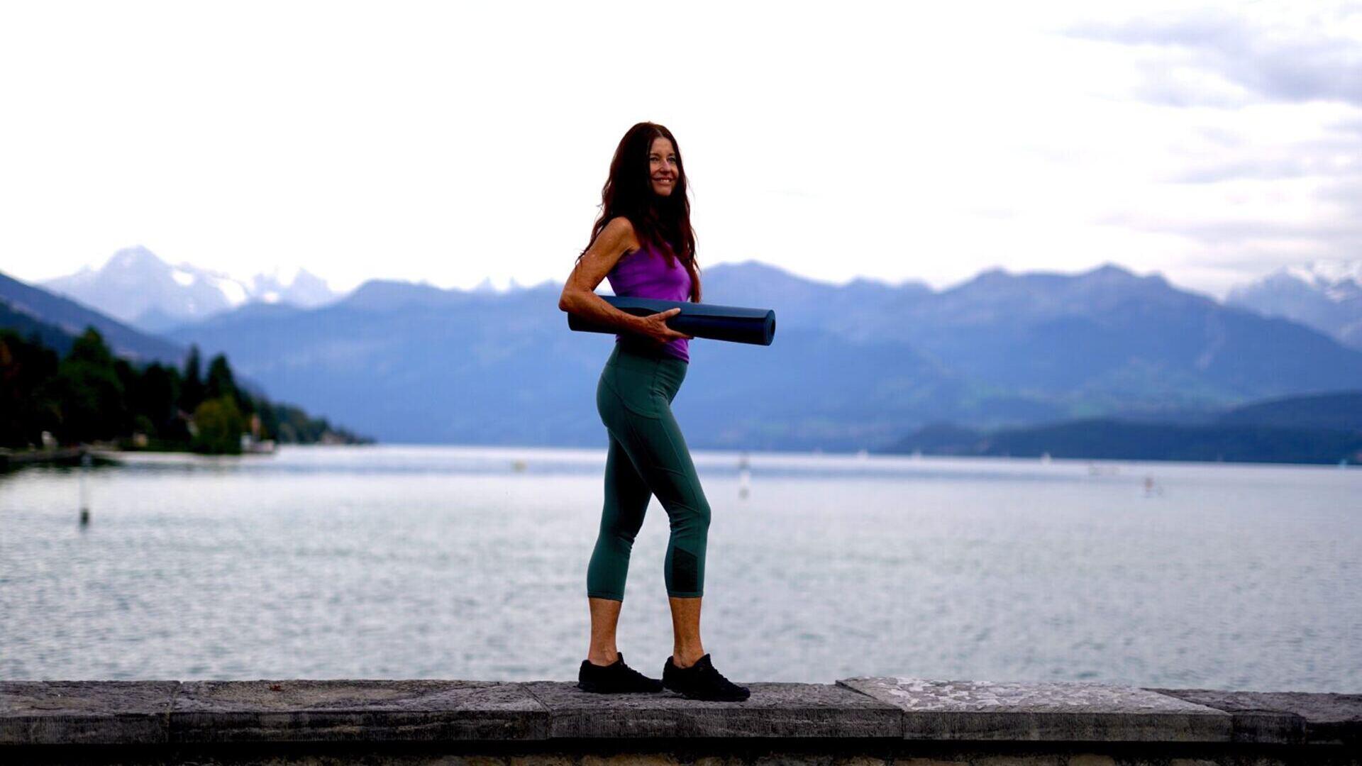 Claudia Eva Reinig mit Yogamatte vor See in Thun