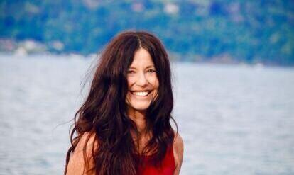 Yogalehrerin Claudia Eva Reinig mit Yogamatte unter dem Arm, im Hintergrund Schloss Schadau