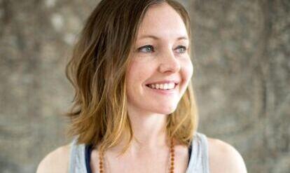 Yogalehrerin Laura Burns, Portrait mit grauem Shirt und Malakette
