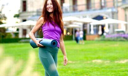 Yogalehrerin Claudia Eva Reinig mit Yogamatte unter dem Arm, im Hintergrund Schloss Schadau