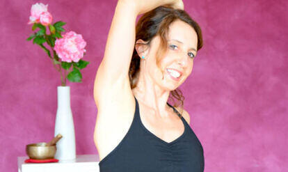 Yogalehrerin Barbara in einer Yogastellung, links im Bild rosa Blumen