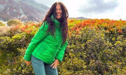 Yogalehrerin Claudia Eva Reinig in grüner Jacke im Herbst vor leuchtenden Berge 