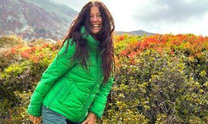 Yogalehrerin Claudia Eva Reinig in grüner Jacke im Herbst vor leuchtenden Berge 