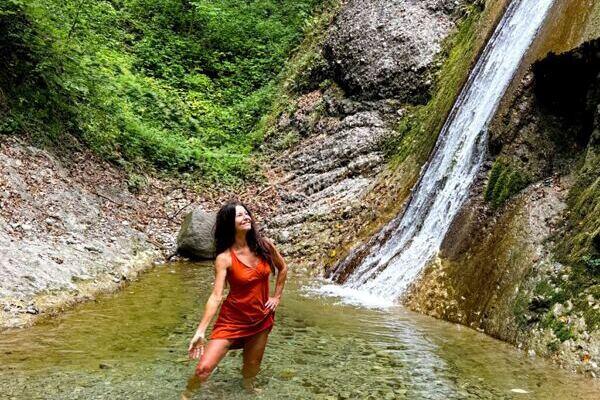 Claudia Eva Reinig ist beim Yoga Retreat in einem grünen Becken mit wasserfall