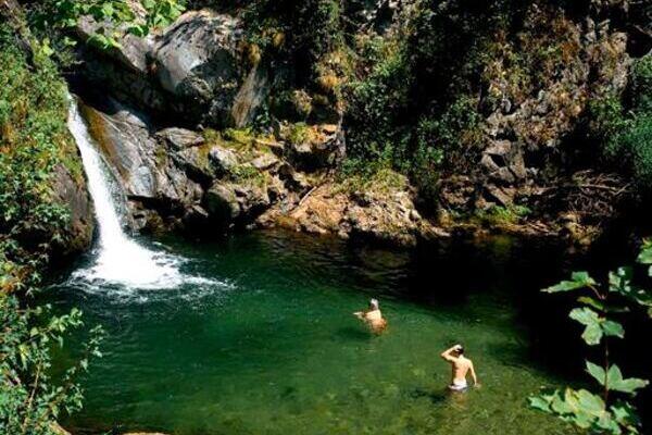 Wasserfall in der Natur mit Yogateilnehmern davor die baden