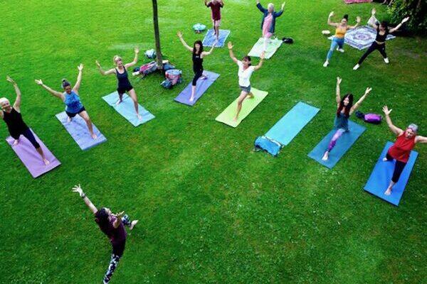 Yogaübende im Freien von oben, sie üben die Yogastellung Held, auf bunten Yogamatten