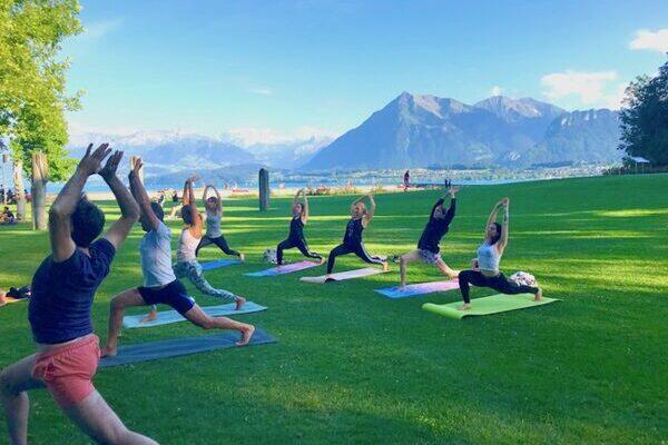 Menschen die Yoga im Freien üben, im Schadaupark in Thun, im Hintergrund der Berg Niesen