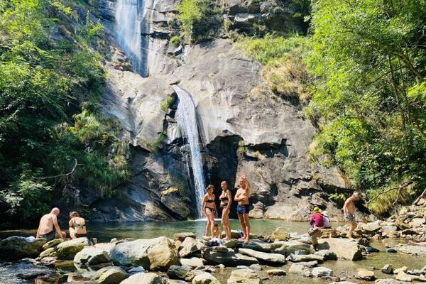 Wasserfall in der Natur mit Yogateilnehmern davor die baden