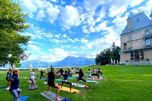 Gruppe die Yoga im Schaudaupark vor dem Schloss übt in Thun, Schweiz, 