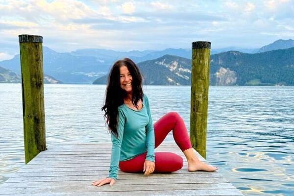 Claudia Eva Reinig sitzt im Yogasitz auf einem Holzsteg am Vierwaldstättersee