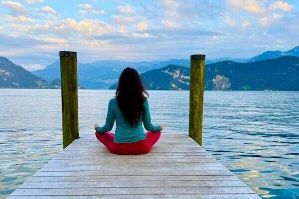 Claudia Eva Reinig sitzt im Yogasitz auf einem Holzsteg am Vierwaldstättersee