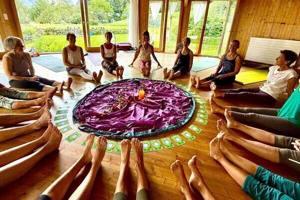 Yogasaal Yogafrauen, die im Kreis sitzen, Fensterfront Blick auf die Wiese
