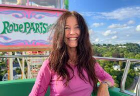 Yogalehrerin Claudia Eva Reinig in einer Riesenrad Gondel. Im Hintergrund der Blick von oben auf Bäume und die Welt.