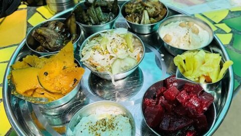 Ayurvedischer Gemüseteller mit verschiedenen Schalen wie Kürbisgemüse, Kraut, Rote Beete, Kichererbsen