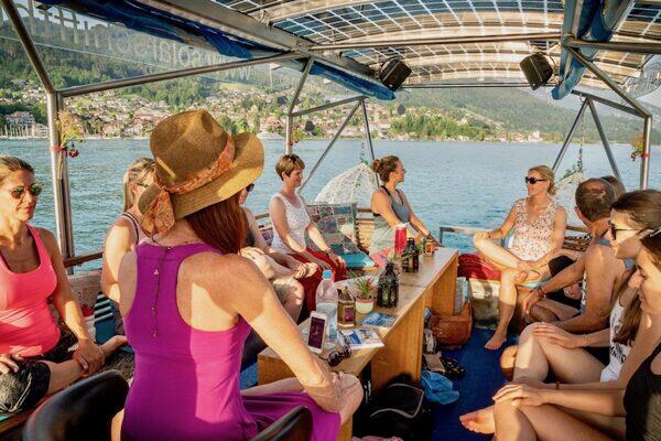 Gruppe von menschen im Sommer, die im Solarboot auf dem Thunersee sitzen, Claudia Eva Reinig mit rosa Sommerkleid und Sonnenhut