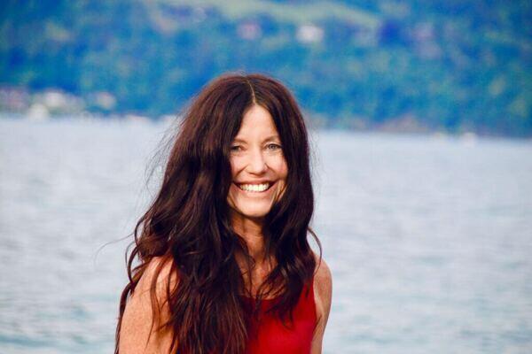 Yogalehrerin Claudia Eva Reinig in roter Yogakleidung, im Hintergrund der Thunersee